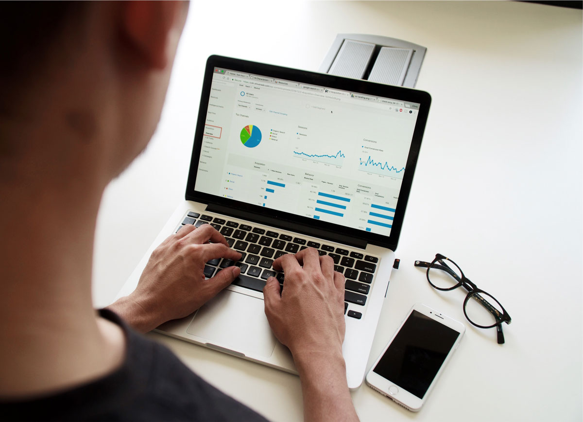 Un hombre digitando en un notebook donde se pueden ver gráficos generados por un sistema big data.